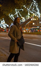 Young Woman Getting A Taxi On The Street At Night