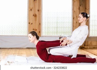 Young woman getting traditional thai stretching massage by therapist 