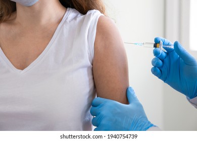 Young woman getting a vaccine in a doctor's office - Shutterstock ID 1940754739
