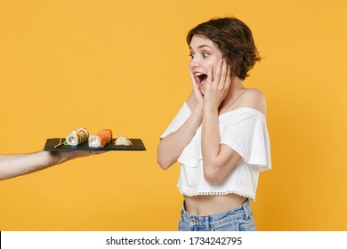 Young Woman Girl In Casual Clothes Hold In Hand Gives Takes Makizushi Sushi Roll Served On Black Plate Traditional Japanese Food Isolated On Yellow Background Studio Portrait People Lifestyle Concept