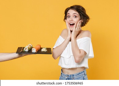 Young Woman Girl In Casual Clothes Hold In Hand Gives Takes Makizushi Sushi Roll Served On Black Plate Traditional Japanese Food Isolated On Yellow Background Studio Portrait People Lifestyle Concept