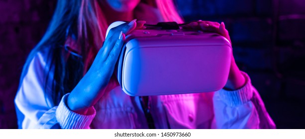 Young Woman Girl Gamer Hold Vr Headset Ar Innovative Glasses Goggles Watch 3d 360 Video Play Game In Futuristic Purple Neon Light, Virtual Augmented Reality Technology Concept, Close Up View, Banner