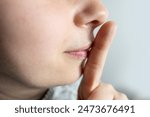 Young woman, girl making hush gesture, signaling for silence, lips, asking for quiet and privacy, private moment, keeping secrets, silent signal
