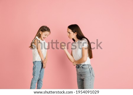 Young woman and girl, mother and daughter isolated over pink background.