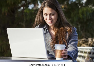 A Young Woman Or Girl Student Using A Laptop Outside And Drinking Takeaway Coffee