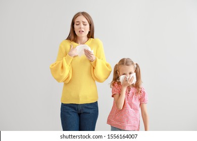 Young woman and girl suffering from allergy on light background - Powered by Shutterstock