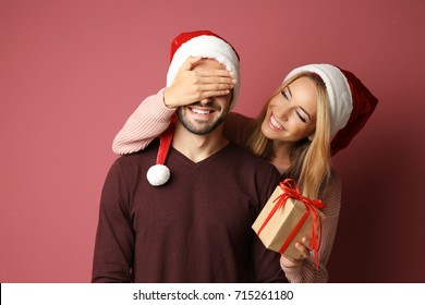 Young Woman Giving Her Boyfriend Christmas Present, On Color Background