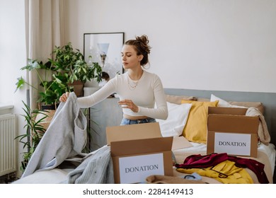 Young woman giving her clothes to charity. - Powered by Shutterstock