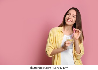 Young woman with glass of lemon water on pink background. Space for text - Shutterstock ID 1573424194