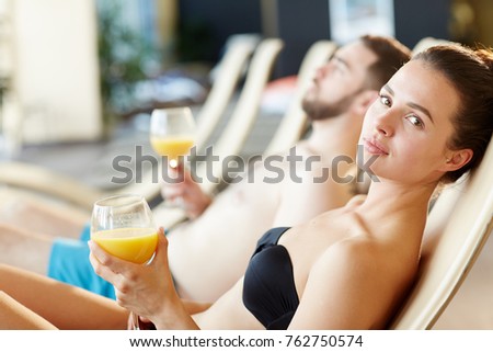 Young woman with glass of orange juice enjoying her vacation at spa resort