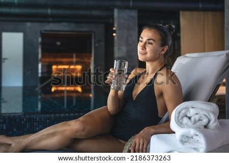 A young woman with a glass of water after the sauna is resting, the concept of a spa complex.