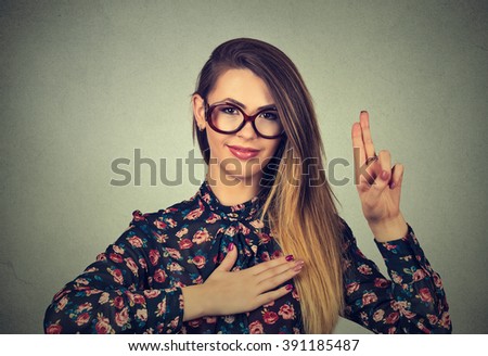 Young woman in glasses making a promise isolated on gray wall background 
