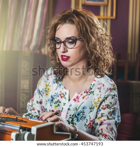 Young woman with glasses, sitting at a typewriter, portrait