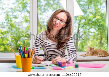 Young woman with glasses writing in a notebook, the account funds. Remote work.