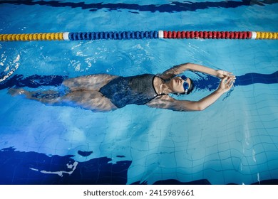 Young woman in goggles swimming on back in the pool	 - Powered by Shutterstock