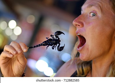Young woman going to taste o scorpion, Thailand