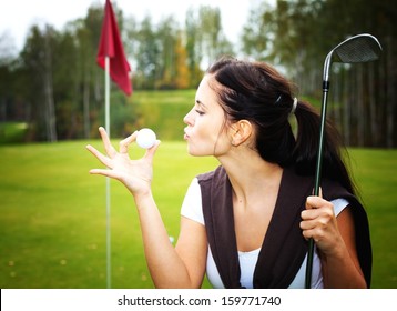 Young woman golf player on green kissing ball