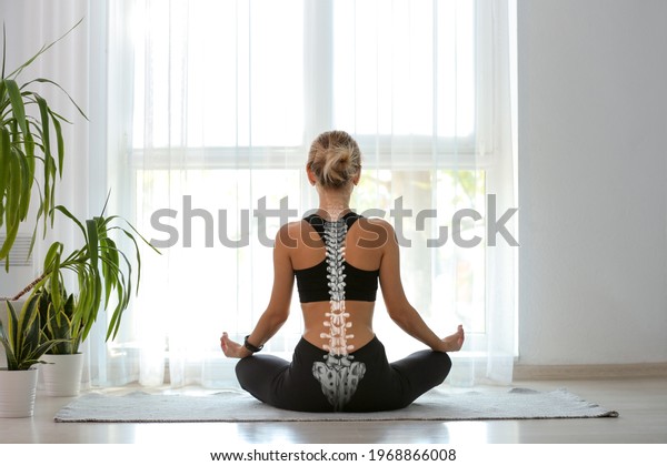 Young woman with good posture meditating at home,
back view
