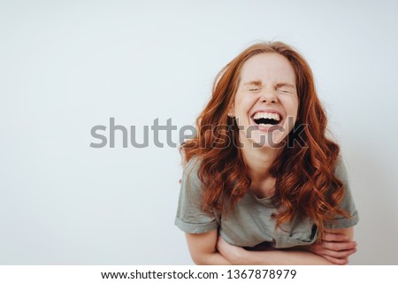 Young woman with a good sense of humor enjoying a laugh screwing up her eyes in amusement over white with copy space
