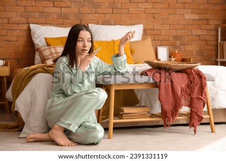 Young woman gossiping by mobile phone in bedroom