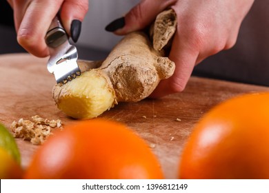 Young Woman In A Gray Apron Peeling A Ginger Root