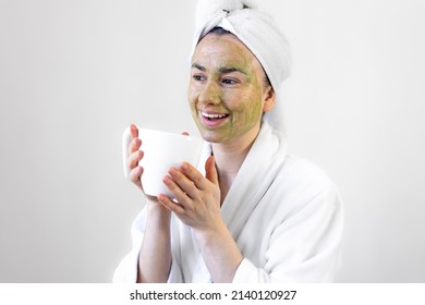 Young Woman With A Green Beauty Mask On Her Face And With A Cup.