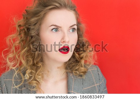 Young woman with green eyes over red background. Total SALE concept. Close up portrait of crazy and excited girl with big eyes
