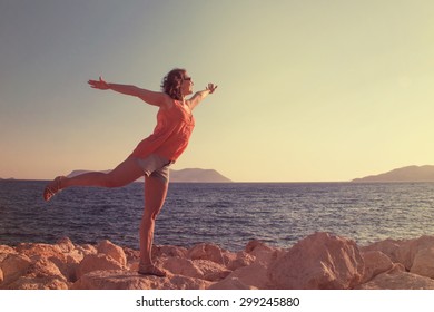 Young woman greets the sun on the beach
