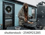 A young woman is grilling a barbecue outside her house in winter. natute. Lifestyle. the concept of a winter holiday in nature