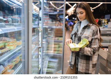 Young Woman In The Grocery Shop During Choosing And Buying Fresh Chicken Eggs 