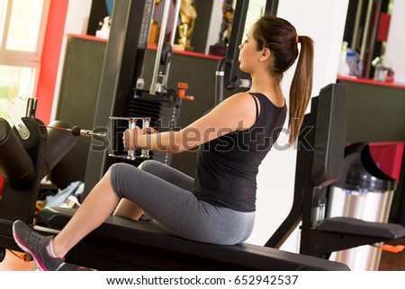 Young woman in the gym and exercising Back on machine