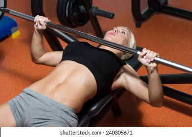 Young Woman In Gym Exercising On The Bench Press