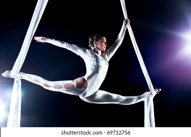 Young woman gymnast. On black background with flash effect.