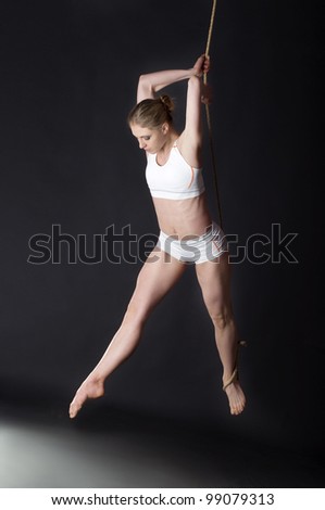 Young woman gymnast on black background