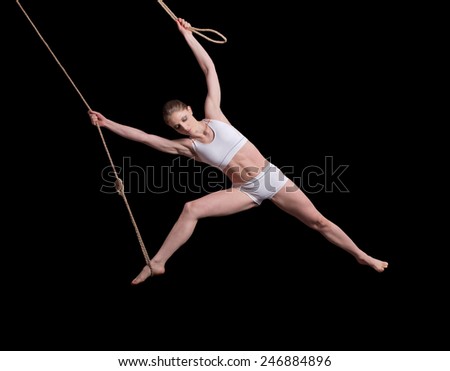 Young woman gymnast on rope on black background 