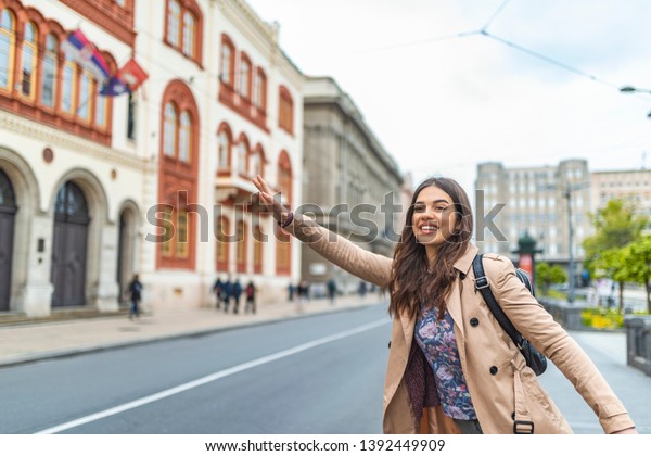 Young woman hailing a taxi\
ride. Beautiful charming woman hailing a taxi cab in the street.\
Businesswoman trying to hail a cab in the city. Tourist woman\
hailing a taxi