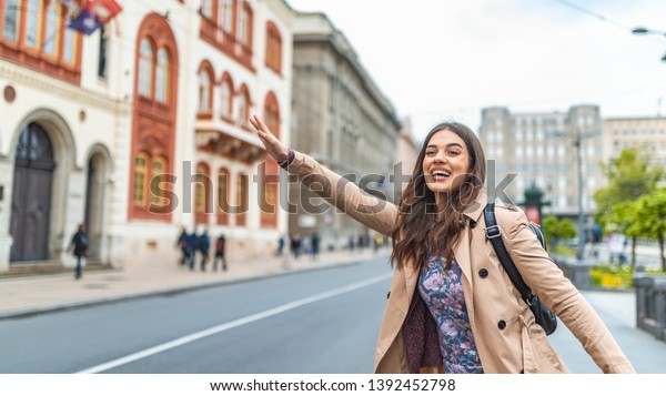 Young woman hailing a taxi
ride. Beautiful charming woman hailing a taxi cab in the street.
Businesswoman trying to hail a cab in the city. Tourist woman
hailing a taxi