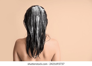 Young woman with hair mask on beige background, back view - Powered by Shutterstock