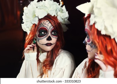 Young woman with Halloween sugar skull makeup looking on reflection in the mirror. Street portrait. Close up