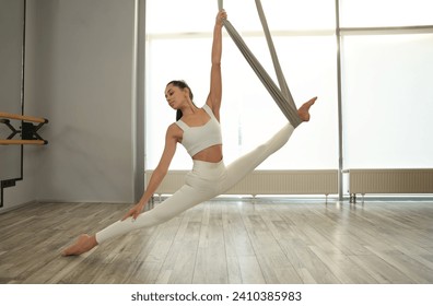 Young woman with hammock practicing fly yoga in studio - Powered by Shutterstock