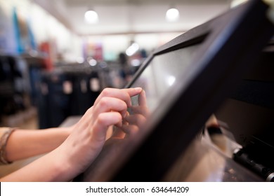 Young Woman Hand Charging A Payment For A Some Clothes By Touchscreen Treasury At Huge Shopping Centre (color Toned Image)