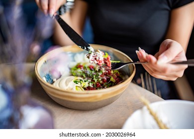 Young Woman Hand Eating Beef Tartare Using Knife And Fork Fom Bowl