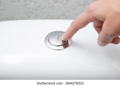 Young woman hand finger pushing button in toilet. Closeup.