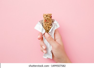 Young woman hand holding cereal bar on pastel pink table. Opened white pack. Closeup. Sweet healthy food. - Shutterstock ID 1499507582