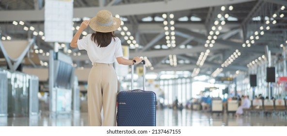 Young woman hand holding luggage handle before checking flight time in airport, Transport, insurance, travel and vacation concepts - Powered by Shutterstock