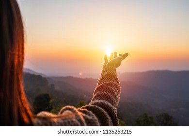 Young woman hand reaching for the mountains during sunset and beautiful landscape