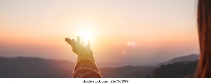 Young woman hand reaching for the mountains during sunset and beautiful landscape - Shutterstock ID 2167601099