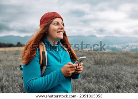 Young woman hand with smartphone catching signal at mountains. Road trip, transport, travel, technology and people concept. High quality photo