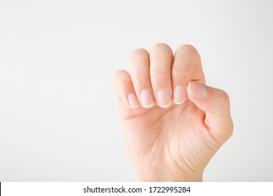 Young Woman Hand Without Nail Polish On Light Gray Background. Showing Healthy Natural Nails. Simple Manicure. Closeup. Empty Place For Text.