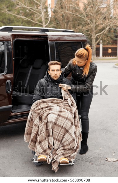 Young\
woman with handicapped man in wheelchair\
outdoors